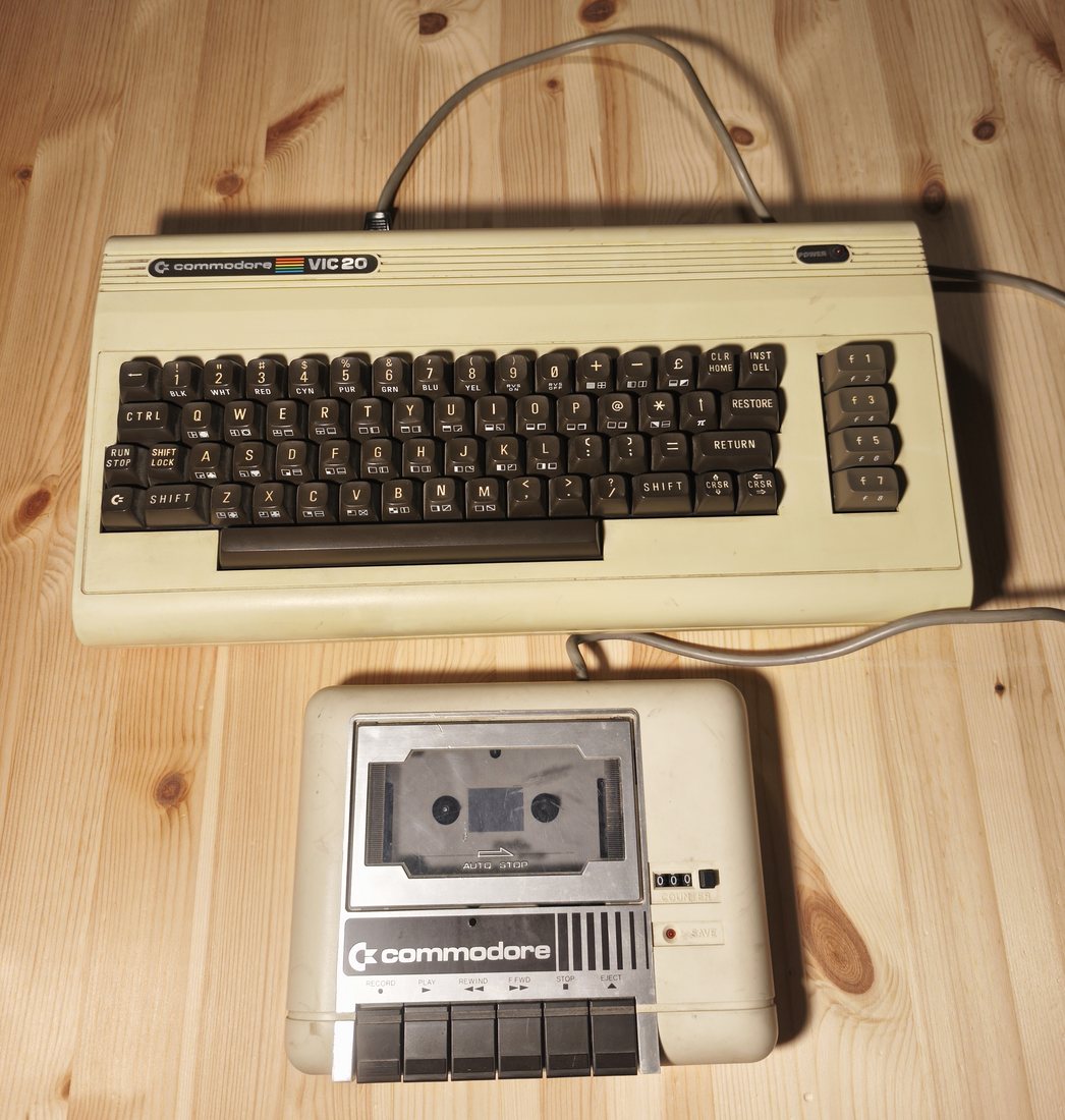 Un Commodore VIC-20 con il registratore a cassette Datassette, appoggiati su un piano di legno.