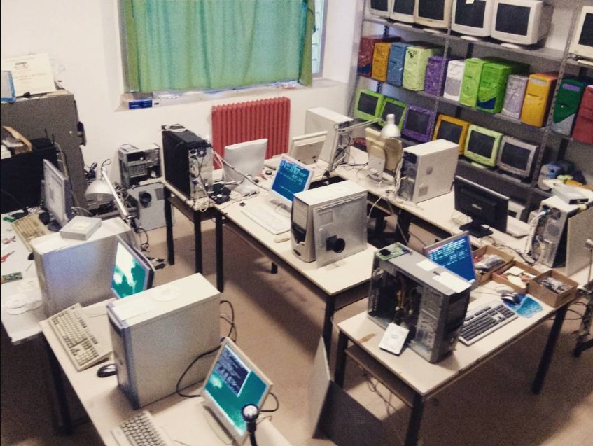 Il primo laboratorio DejaVu: banchi con computer smontati, monitor accesi e scaffali pieni di case colorati.