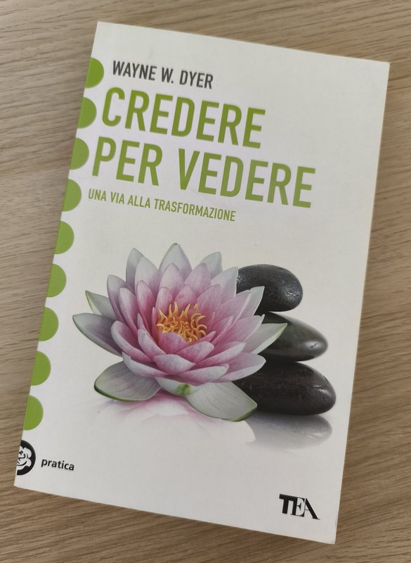 La copertina del libro Credere per Vedere di Wayne W. Dyer, appoggiato su un tavolo di legno.